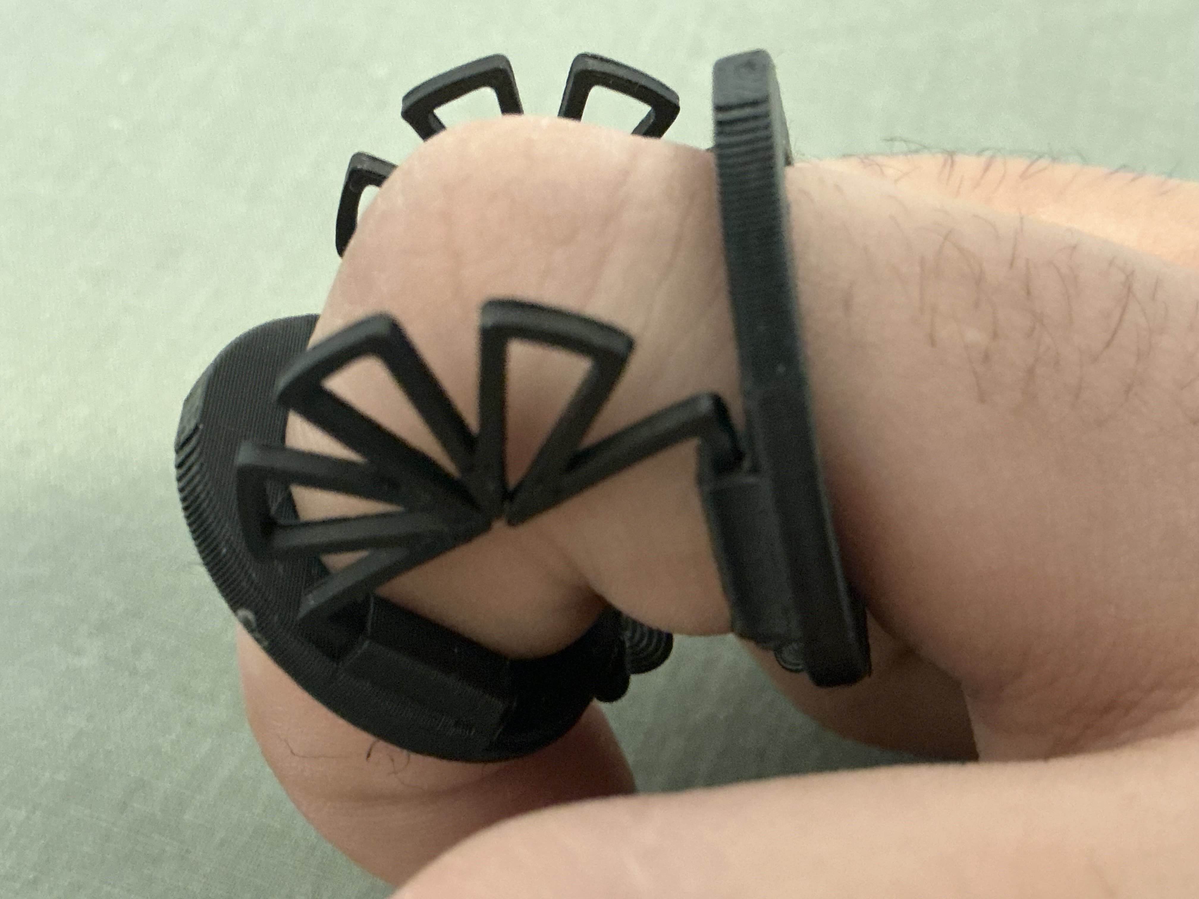 The black printed compliant joint worn on a bent finger, its open triangular cells folded around the knuckle